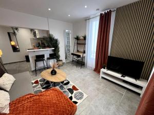 een woonkamer met een bank en een flatscreen-tv bij Le Japandi - Cosyloc Agency - Aux Portes de Paris in Pantin
