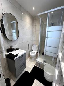 een badkamer met een toilet, een wastafel en een spiegel bij Le Japandi - Cosyloc Agency - Aux Portes de Paris in Pantin