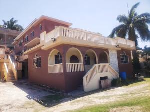 a large house with a balcony and a palm tree at Comfy Apartments in Montego Bay