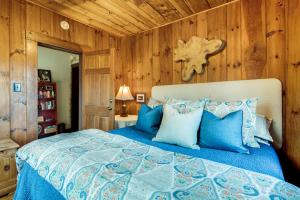 - une chambre avec un lit bleu et des murs en bois dans l'établissement Peaceful Hendersonville Cabin - Hot Tub and Fire Pit, à Hendersonville