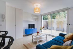 a living room with a blue couch and a table at P'tit Garden / JO 2024 / Paris/ Stade de FRANCE in Aulnay-sous-Bois