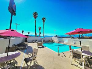 a swimming pool with tables and chairs and umbrellas at Motel 6-Palm Desert, CA - Palm Springs Area in Bermuda Dunes