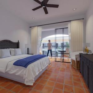 Un hombre caminando en un dormitorio con una cama y un balcón en Tropicana Los Cabos, en San José del Cabo
