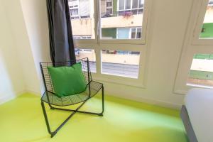 a chair with a green pillow sitting in front of a window at Koala Hostel Mercado in Alicante