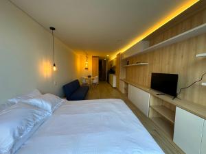 a bedroom with a large white bed and a television at Increible apartamento cerca de Centro Chia y U Sabana in Chía