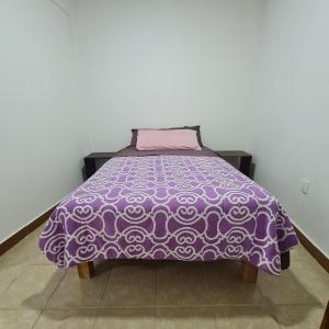 a purple bed with a pink blanket on it at Depa Púrpura Caracol in San Antonio de la Cal