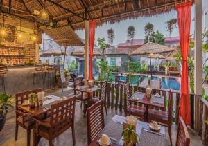 a restaurant with tables and chairs and a pool at Punleu Raksmey Boutique in Siem Reap