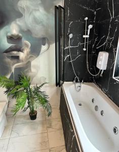 a bathroom with a tub and a painting of a woman at Japandi themed London Apartment in Thornton Heath