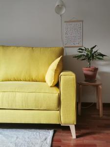 um sofá amarelo numa sala de estar com um vaso de plantas em LA MACETA em Vilagarcía de Arousa