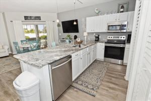 cocina con armarios blancos y encimera de granito en Sandpiper Cove #9124 Condo, en Destin