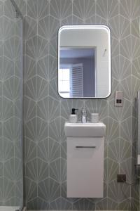 uma casa de banho com um lavatório e um espelho na parede em New, Luxury Apartment in Town Centre em Cheltenham