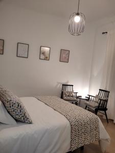 a bedroom with a bed and two chairs and a chandelier at LIVING CAZORLA II in Cazorla