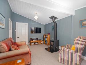 sala de estar con sofá y estufa de leña en Crabapple Cottage - Coromandel Town Holiday Home, en Coromandel