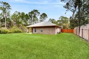 a small house in a yard next to a fence at Emerald Coast Cottage in Navarre