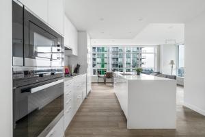 - une cuisine avec des placards blancs et un îlot blanc dans l'établissement Urban Oasis: Stylish Apartment Retreat at UBC, à Vancouver