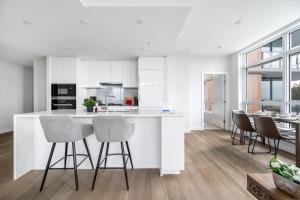 a kitchen with white cabinets and bar stools at Urban Oasis: Stylish Apartment Retreat at UBC in Vancouver