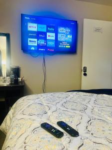 dos controles remotos sentados en una cama con TV en la pared en Wonderful Private Queen Bedroom, en Santa Clara