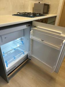 um frigorífico vazio com a porta aberta numa cozinha em Japandi themed London Apartment em Thornton Heath