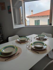 einen Esstisch mit Tellern und Gläsern sowie ein Fenster in der Unterkunft Casa Seamus Briatico in Briatico