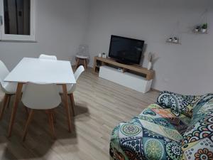 ein Wohnzimmer mit einem Sofa, einem Tisch und einem TV in der Unterkunft Casa Seamus Briatico in Briatico