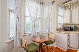 uma cozinha com mesa, cadeiras e janelas em Charming Historic District Parlor Level Apartment em Savannah