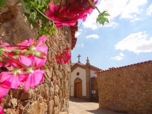 eine Kirche mit rosa Blumen vor einer Wand in der Unterkunft Casas do Juizo - Country Houses in Juizo