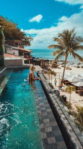 a woman standing in a swimming pool next to a beach at Marilyn Pousada Morro in Morro de São Paulo