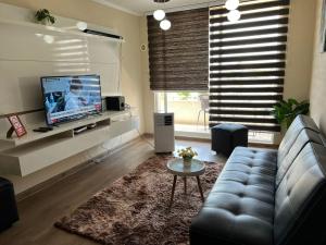sala de estar con sofá y TV en Amplio y Cómodo Departamento K con Estacionamiento Privado, en Rancagua