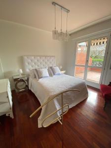 a white bedroom with a large bed and a window at Apartamento con Jardín in Getxo