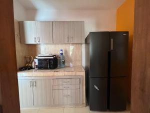 Elle comprend une petite cuisine équipée d'un réfrigérateur noir et de placards. dans l'établissement Villa spacieuse et agréable, à Dakar