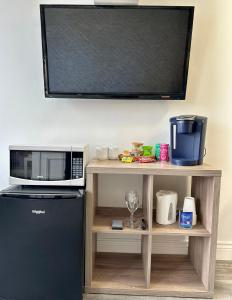 a kitchen with a microwave and a tv on a shelf at Cheticamp Outback Inn in Chéticamp