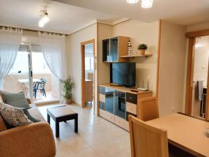 a living room with a couch and a television at Apartamento Neptuno Sunrise Magic World in Oropesa del Mar