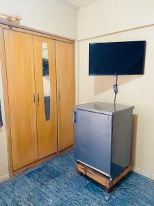 a room with a television and wooden cabinets at Tuxedo Hotel in Accra