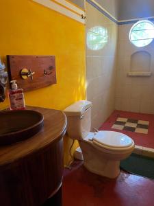 a bathroom with a white toilet and a sink at Buena Onda Backpackers in San Juan del Sur