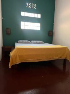 sypialnia z łóżkiem z żółtym kocem w obiekcie Buena Onda Backpackers w mieście San Juan del Sur