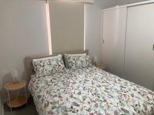um quarto com uma cama com um edredão e almofadas florais em Herbert Cottage em Tumut