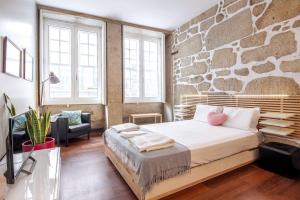 una camera con letto e parete in pietra di OHH - Ganesha studio- Oporto Center a Porto