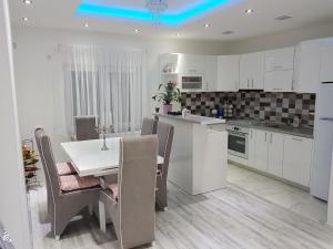 a kitchen with white cabinets and a table and chairs at Apartman TT Stan na dan Trn Laktaši in Laktaši