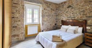 - une chambre avec un lit et un mur en pierre dans l'établissement AG Casa Do Castro en rural Galicia a 14km de playa, à Esto