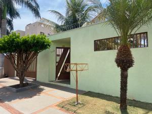 uma casa verde com palmeiras em frente em Casa Camargo - mobiliada, cozinha completa em Campo Grande