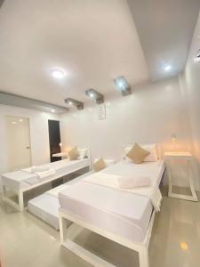 a white room with two beds and two tables at REGIE Homestay Vigan City in Aggay