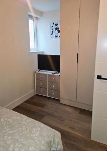 a bedroom with a bed and a television on a dresser at 1-bed flat near Romford station in Romford