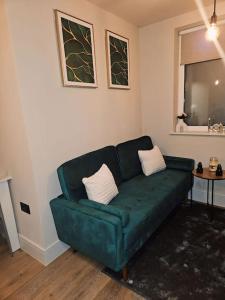 a living room with a green couch and a table at 1-bed flat near Romford station in Romford