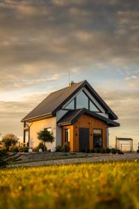 uma casa com um telhado preto num campo em Sunset- Dom zachód słońca Spa em Mołdzie