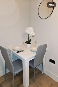 una mesa blanca con sillas y un jarrón de flores. en 1-bed flat near Romford station, en Romford