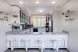 una cocina con armarios blancos y una barra grande con taburetes en Humacao Villa - 8BR, Pool, Palmas, Ocean Views, 