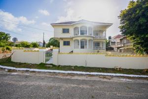 a white house with a white fence in front of it at Sun Haven Villa in Discovery Bay, St. Ann in Discovery Bay
