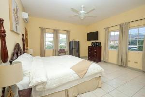 發現灣的住宿－Sun Haven Villa in Discovery Bay, St. Ann，卧室配有白色的床和电视。