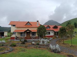 ein Haus mit einem roten Dach und einem Garten in der Unterkunft Refugio de Montaña Huerta Sacha in Chaupi