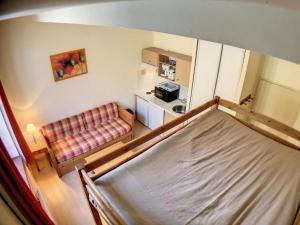 een kleine kamer met een bed en een bank bij Appartement Grand Hôtel Aulus-les-Bains in Aulus-les-Bains